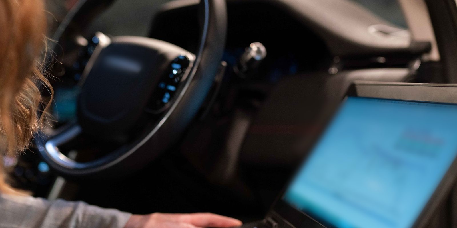 Técnica analisa gráficos num notebook apoiado ao lado do volante de um carro